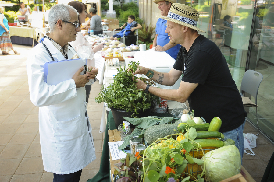 Dr. Mehrdad Shojaei and chef Sebastian Carosi of Coyote Ridge Ranch in La Center talk about produce at the Salmon Creek Farmers Market at Legacy Salmon Creek Medical Center on July 26.