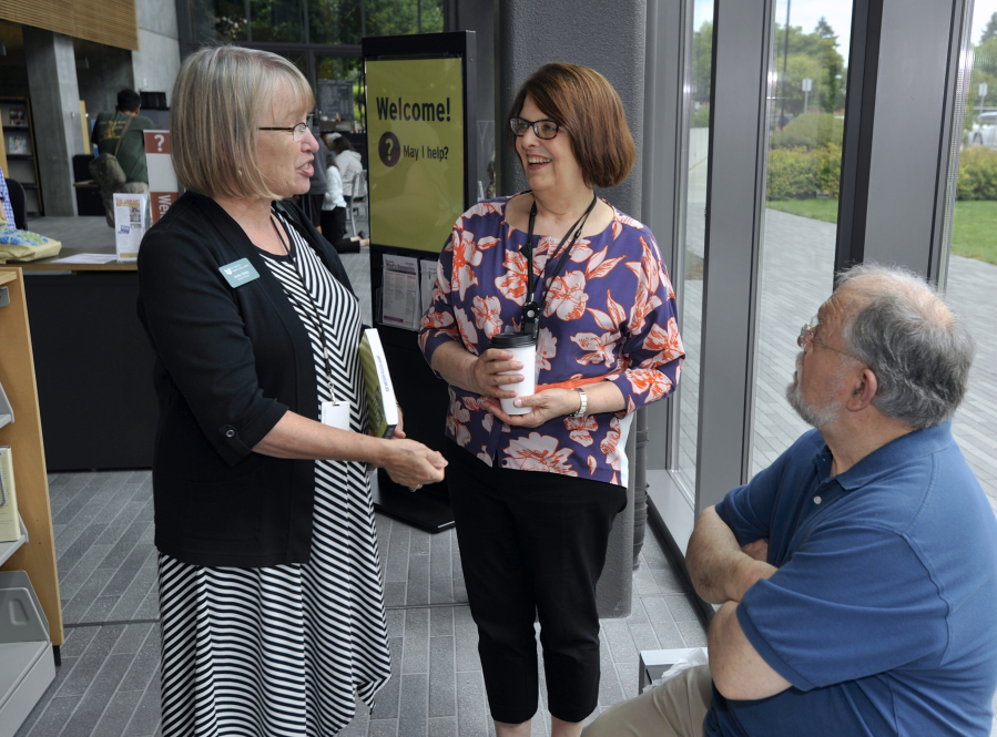 Executive Director Amelia Shelley, left, chats with Branch Manager Jackie Spurlock, center, and Mike Spurlock as people celebrate the fifth anniversary of the downtown Vancouver Community Library.