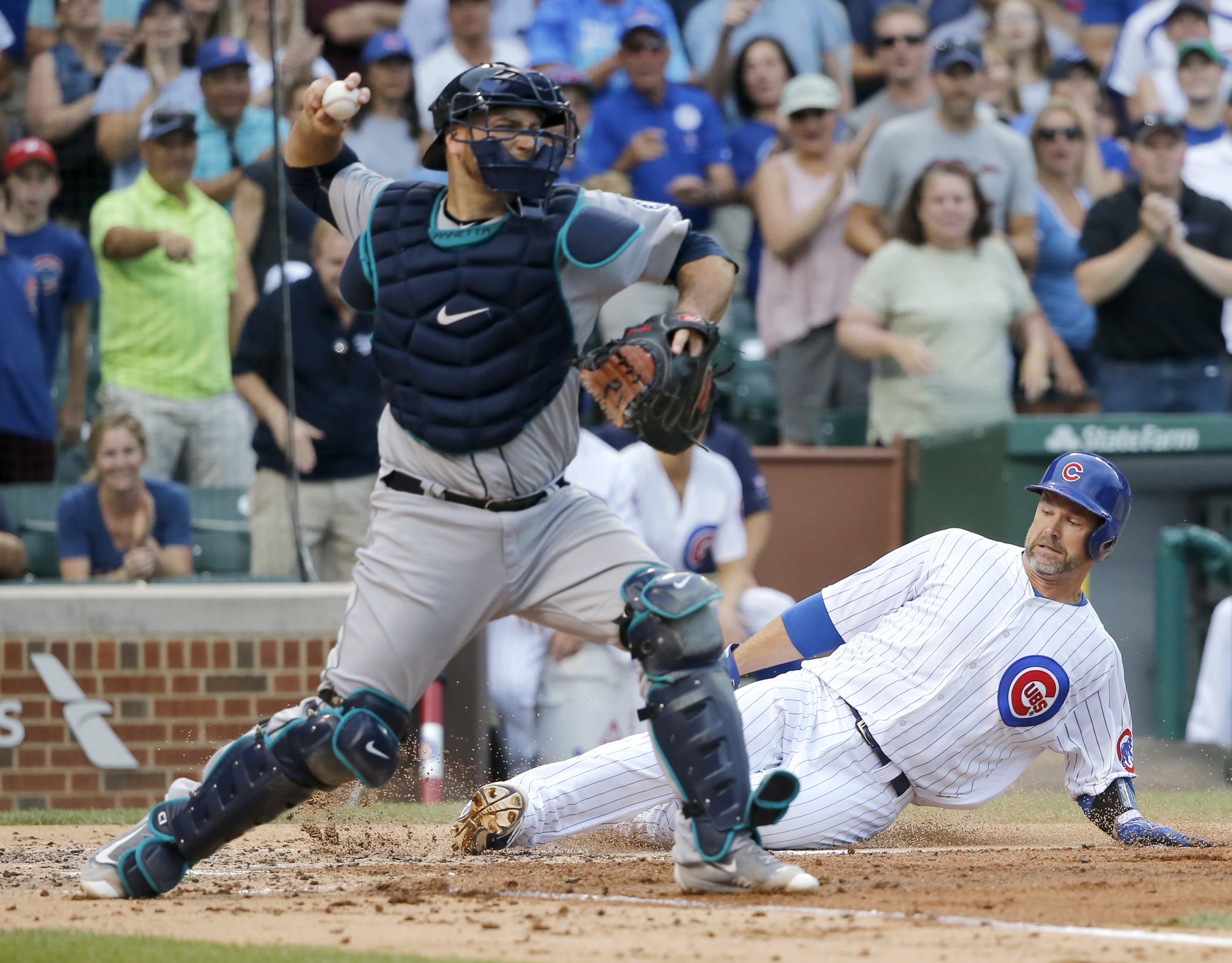 Chicago Cubs' David Ross, right, scores past Seattle Mariners catcher Chris Iannetta on a single by Chris Coghlan as Iannetta tries to get Chris Coghlan at second during the second inning of a baseball game Friday, July 29, 2016, in Chicago. Javier Baez also scored on the play.