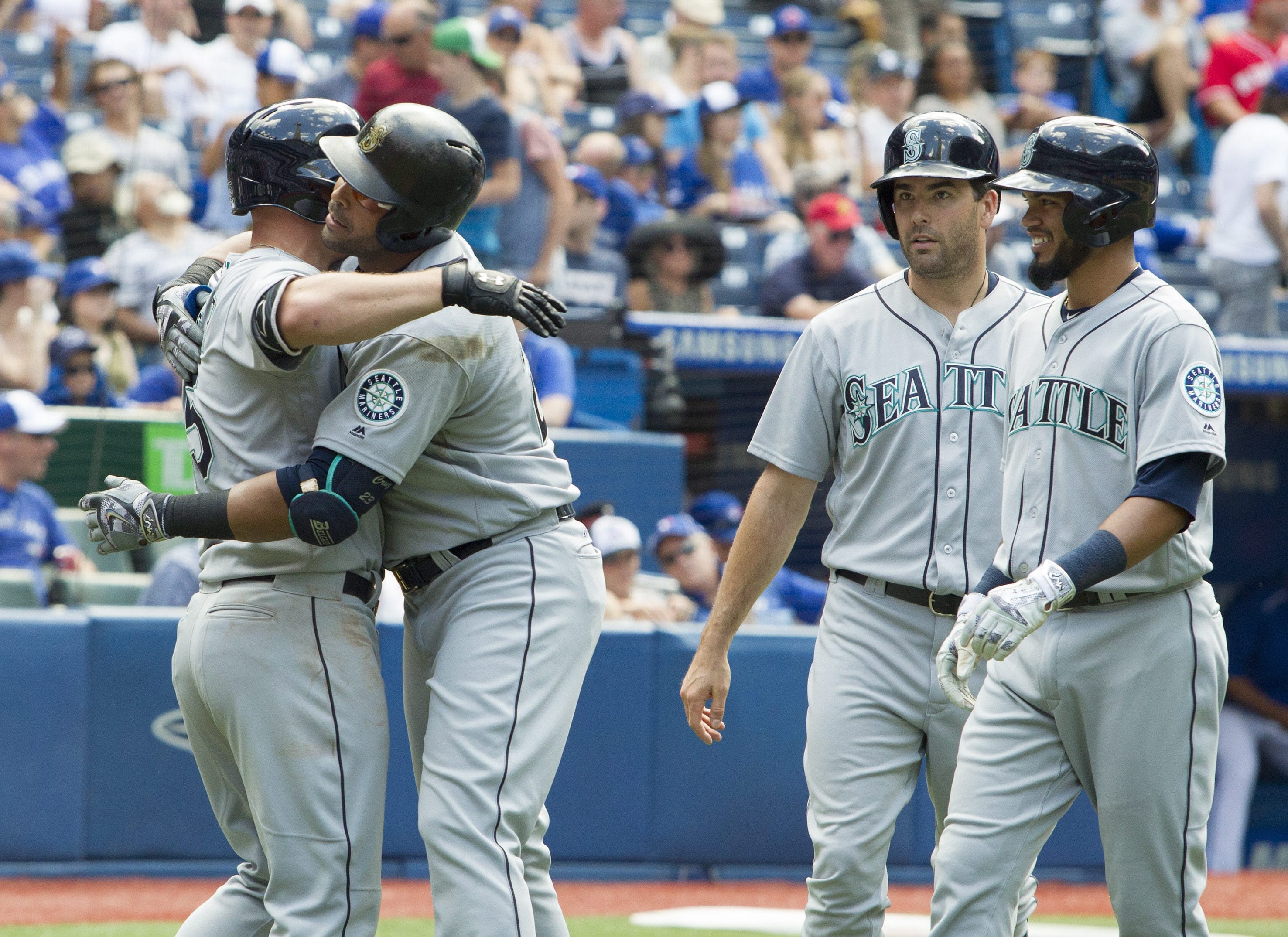 Seattle Mariners' Nelson Cruz, second from left, is embraced by teammate Kyle Seager after hitting a three-run home run in eighth-inning baseball game action against the Toronto Blue Jays in Toronto, Saturday, July 23, 2016.