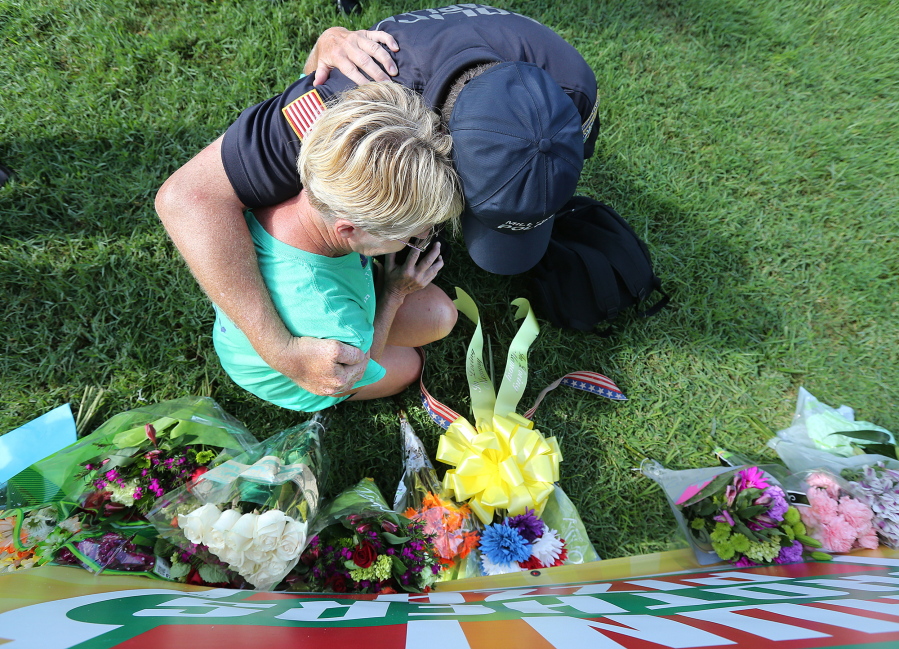 Millville, N.J., Police Chaplain Bob Ossler prays and weeps with a local resident as she places flowers on a memorial at the B-Quik gas station on Monday in Baton Rouge, La.