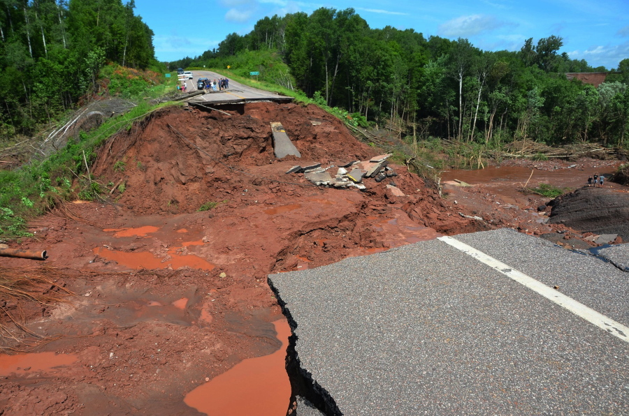 People observe part of Wisconsin Highway 13, washed out after heavy rains, south of Highbridge in Ashland, Wis., Tuesday, July 12, 2016. Storms carrying tornadoes, torrential rain and powerful winds damaged homes, deposited a snowplow in a tree and flooded highways in north-central Minnesota and northern Wisconsin.