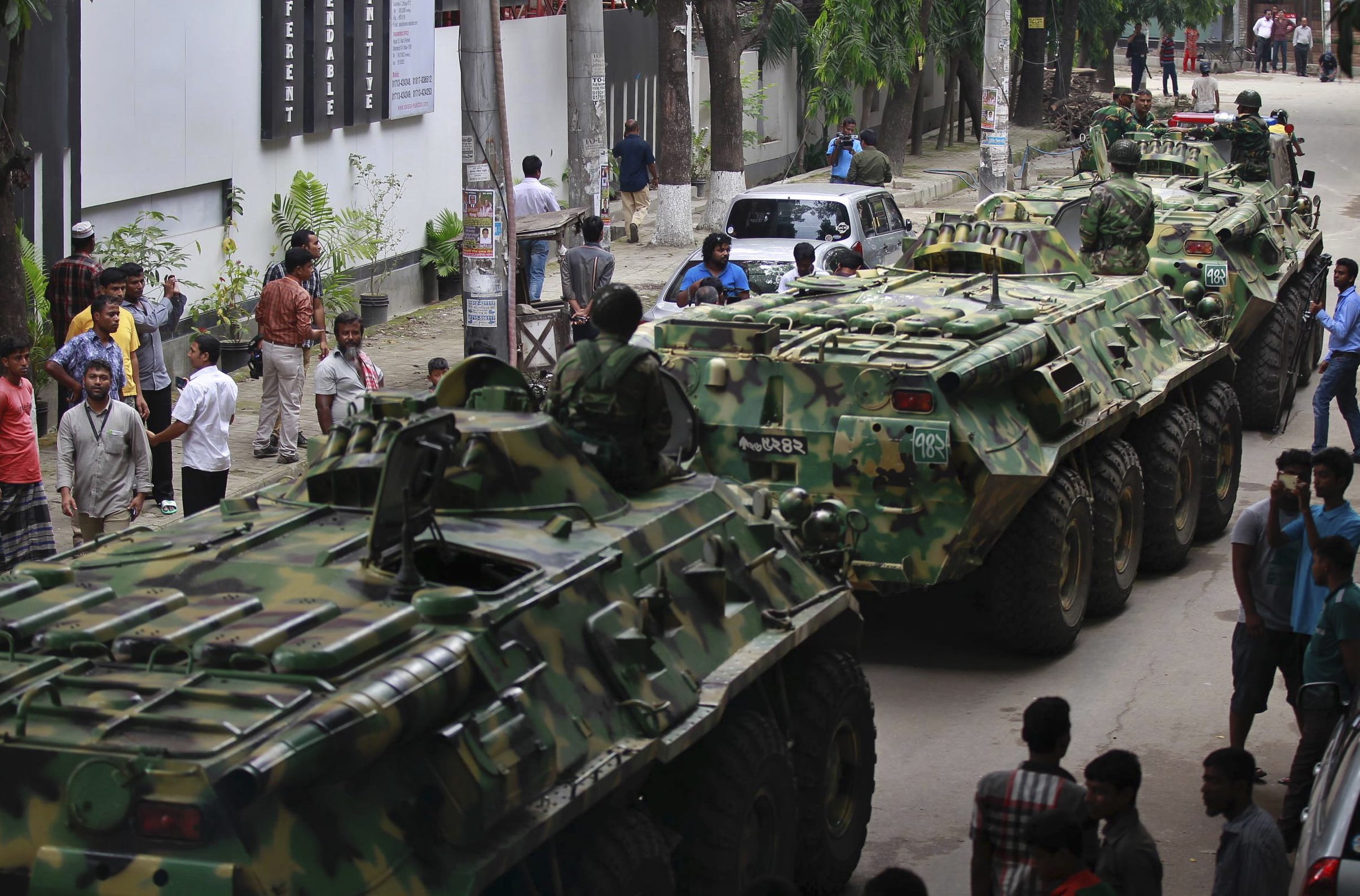 Armored vehicles pass by after an operation against militants who took hostages at a restaurant popular with foreigners in Dhaka, Bangladesh, Saturday, July 2, 2016. Bangladeshi forces stormed the Holey Artisan Bakery in Dhaka's Gulshan area where heavily armed militants held dozens of people hostage Saturday morning, rescuing some captives including foreigners at the end of an hours long standoff.