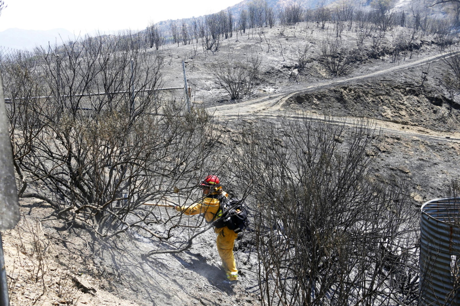 A firefighter clears a hot spot Tuesday near Santa Clarita, Calif., after the Sand Fire swept through over the weekend. The fire is 25 percent contained, officials said Tuesday.
