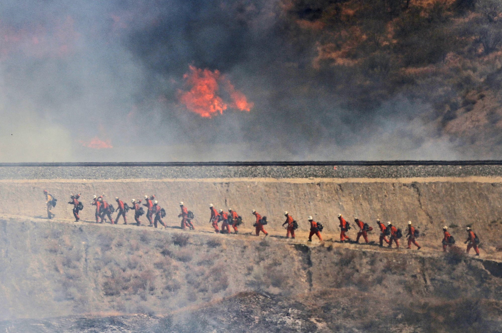 A fire crew approaches as a wildfire burns on Friday, July 22, 2016, in Santa Clarita, Calif. The fire erupted shortly after 2 p.m. Friday next to State Route 14 in Santa Clarita. No homes are immediately threatened, but fire officials say evacuations have been ordered from Soledad Canyon to Agua Dulce Canyon Road.