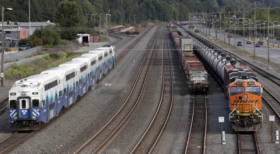 A passenger commuter train, left, passes one of two mile-long oil trains parked adjacent to the King County Airport in Seattle.