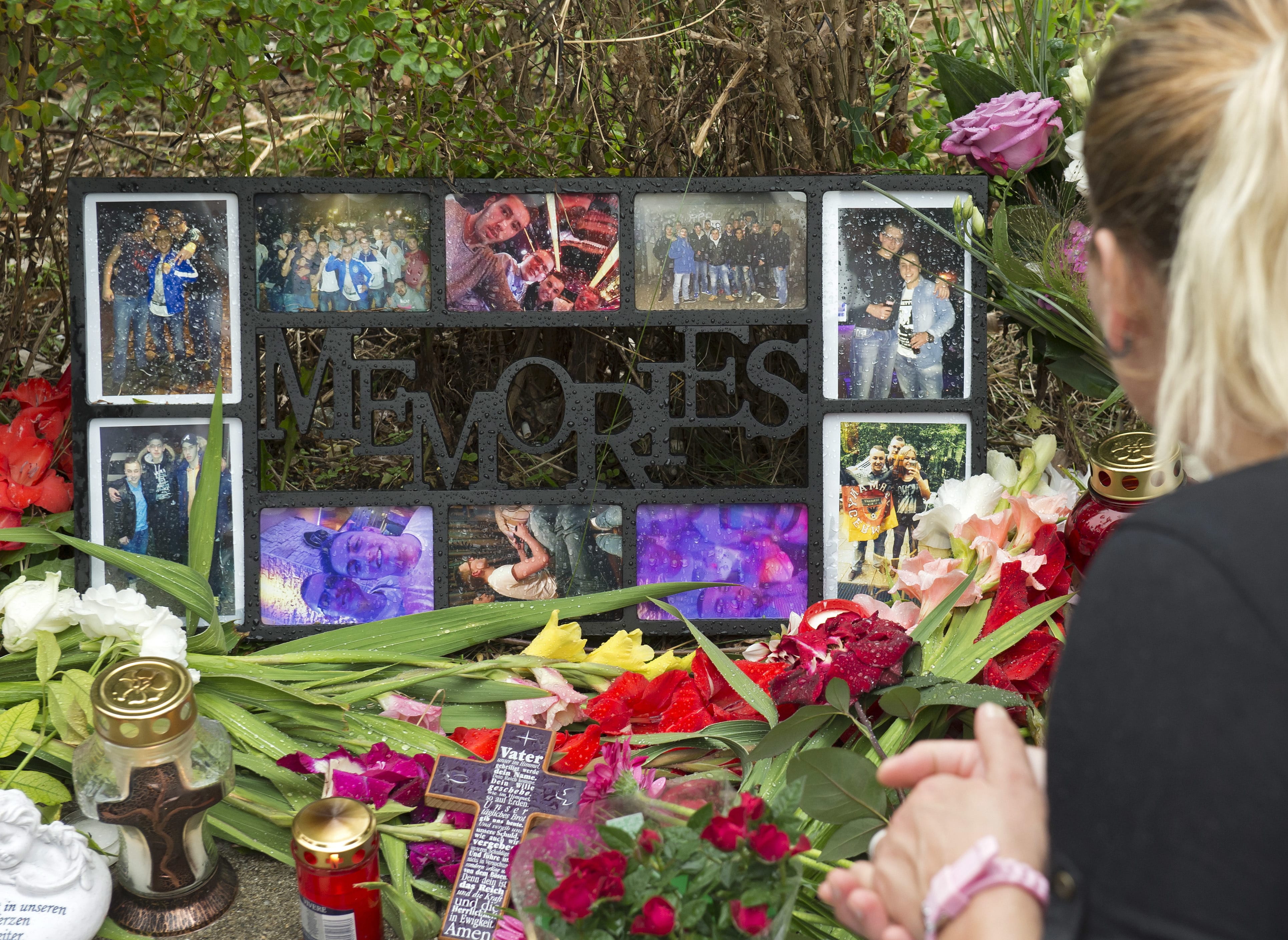 A woman mourns in front of flowers near the Olympia shopping center where a shooting took place leaving nine people dead the day before in Munich, Germany, Saturday, July 23, 2016. Police piecing together a profile of the gunman whose rampage at a Munich mall Friday left nine people dead described him Saturday as a lone, depression-plagued teenager.