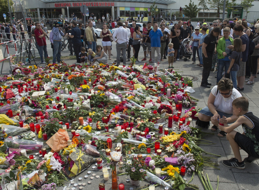 People mourn in front of the Olympia shopping center Sunday where a shooting took place leaving nine people dead two days ago in Munich, Germany.