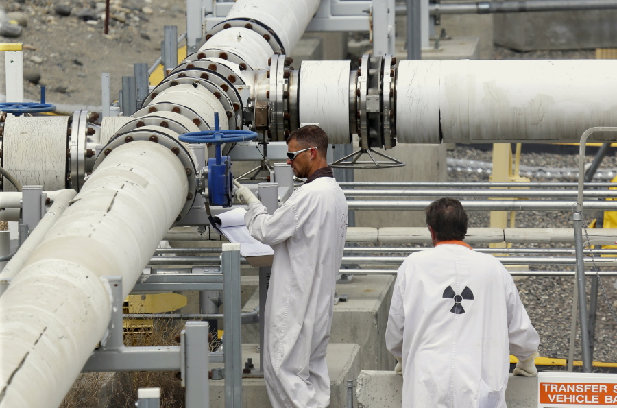 Workers wearing protective clothing and footwear inspect a valve at the &quot;C&quot; tank farm in 2014 on the Hanford Nuclear Reservation near Richland, Wash. The state attorney general is taking legal action Thursday to protect workers who are exposed to chemical vapors on the Hanford Nuclear Reservation. (AP Photo/Ted S.