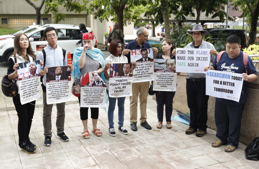 Family members of passengers on board the Malaysia Airlines Flight 370 that went missing on March 8, 2014, hold up placards after a joint press conference Friday by Malaysia, China and Australia in Putrajaya, Malaysia. Malaysia, Australia and China have agreed to suspend the search for Flight 370 once the current area in the Indian Ocean has been completely scoured for the missing Malaysia Airlines jetliner.