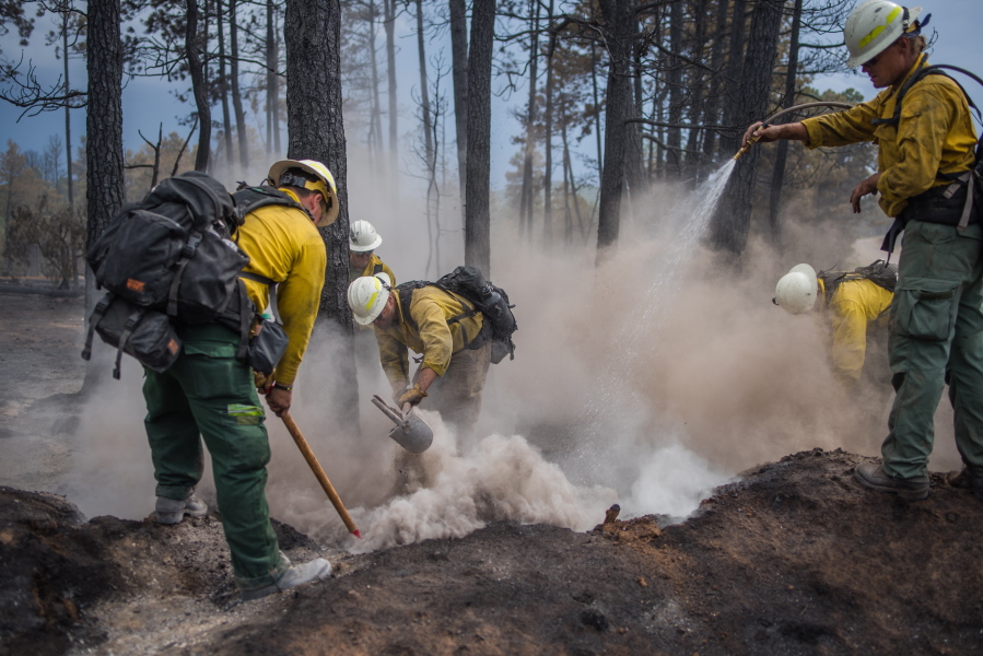 Wildland fire crews from Taos, N.M., put out hot spots Friday in the southern New Mexico village of Timberon. (Roberto E.