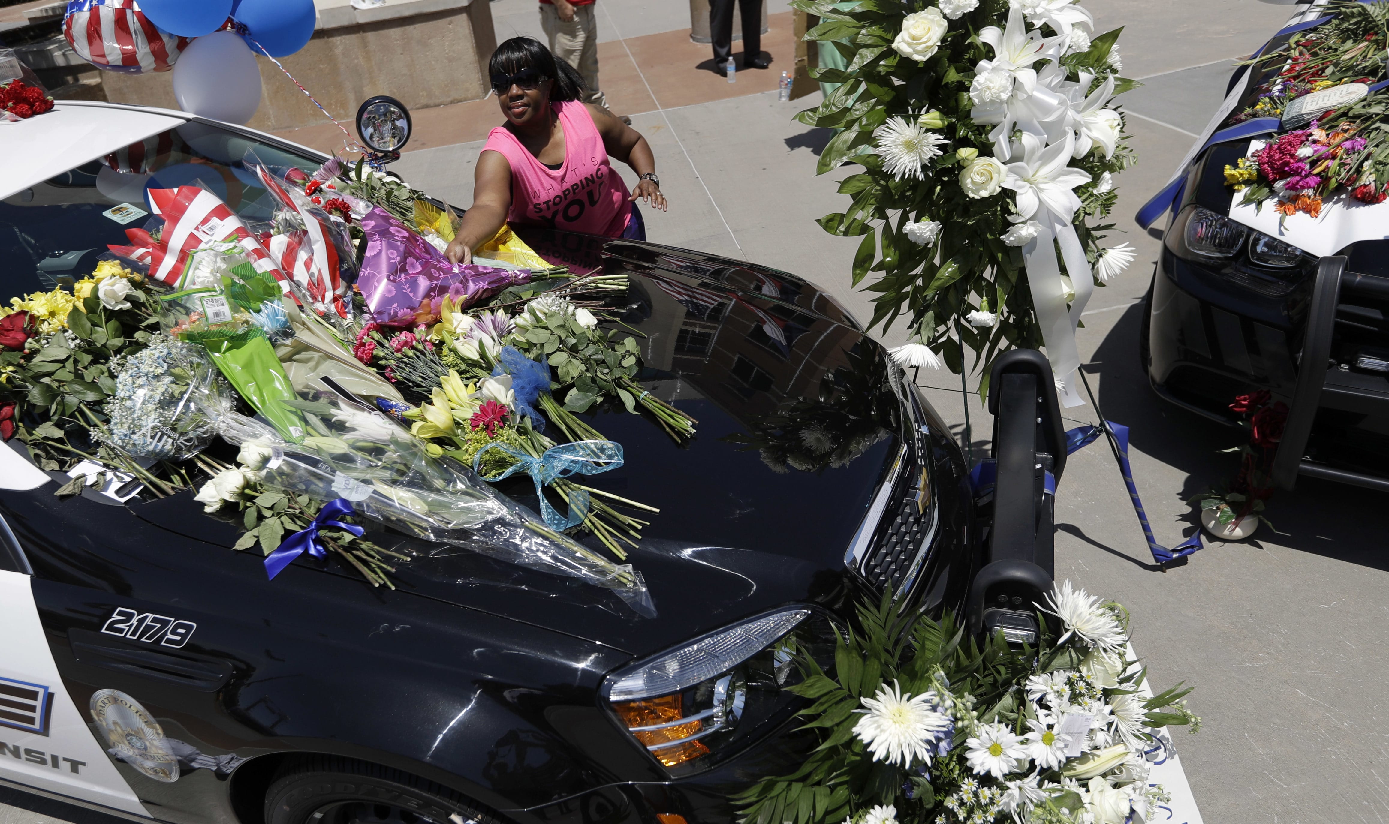Cynthia Ware places flowers on a make-shift memorial at the Dallas police headquarters Friday in Dallas. Five police officers are dead and several injured following a shooting in downtown Dallas Thursday night.