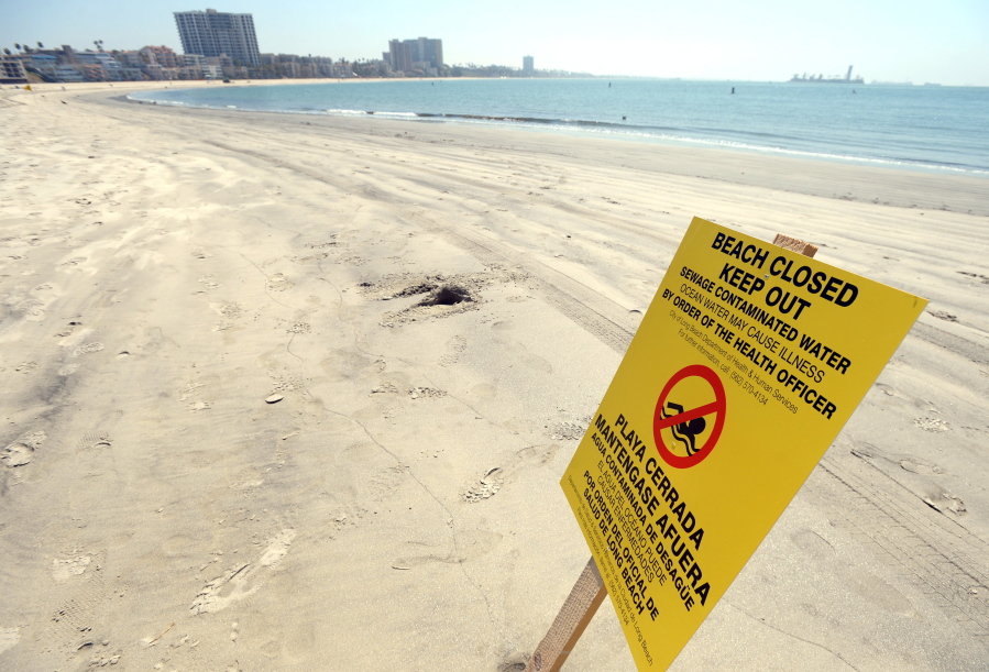A sign is posted at Alamitos Beach warning of the dangers of sewage contaminated water Tuesday in Long Beach, Calif.