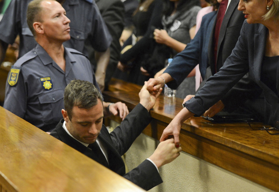 Oscar Pistorius, center, greets family members, right, as he is led down to the cells of the court in Pretoria, South Africa, in 2014. Pistorius is acquitted of murder after a dramatic seven-month trial that is broadcast live around the world. He is instead found guilty of manslaughter for killing Steenkamp and sentenced to five years in prison.