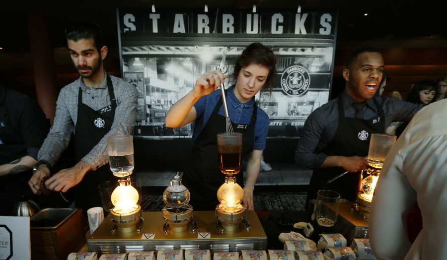 FILE - In this Wednesday, March 23, 2016, file photo, Starbucks workers prepare coffee using siphon vacuum coffee makers at a station in the lobby of the coffee company&#039;s annual shareholders meeting in Seattle. Starbucks says that it will be boosting the base pay of all employees and store managers at U.S. company-run stores by 5 percent or more on Oct. 3. In a letter sent to workers on Monday, July 11, 2016, CEO Howard Schultz said that the amount of the raise will be determined by geographic and market factors. (AP Photo/Ted S.