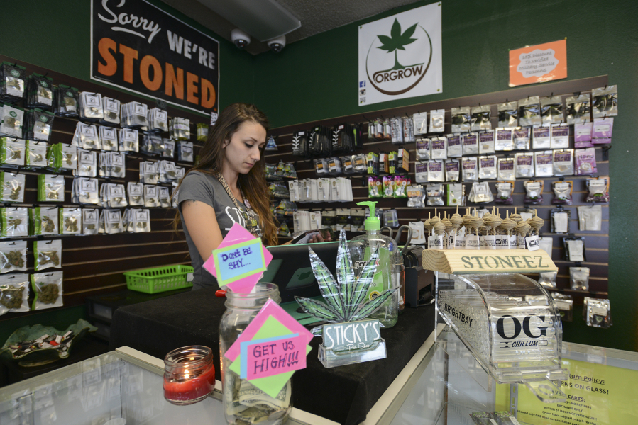Alex Merrell, a manager at Sticky's Pot Shop in Hazel Dell, organizes merchandise Monday. The store must stop selling marijuana after Superior Court Judge Daniel Stahnke upheld a Clark County Hearings Examiner's decision.