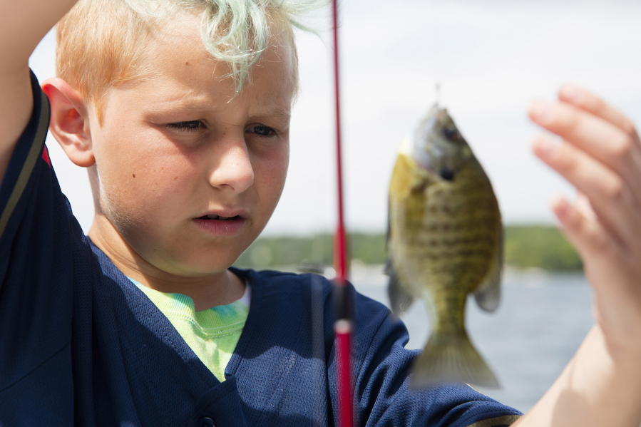 Jake Zickefoose works on detaching a fish to throw back into the water at One Step Summer Camp.