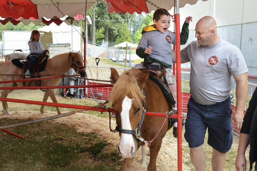Eleven-year-old Cavan Franklin, who has cerebral palsy, rides a pony Monday at the Clark County Fair with the help of Scott Taube, a captain at Clark County Fire District 6, and Cavan&#039;s mom, Brandi Franklin. Cavan was one of six children chosen to participate in the local Memory Makers program, which guides medically fragile children and their families through the fair.