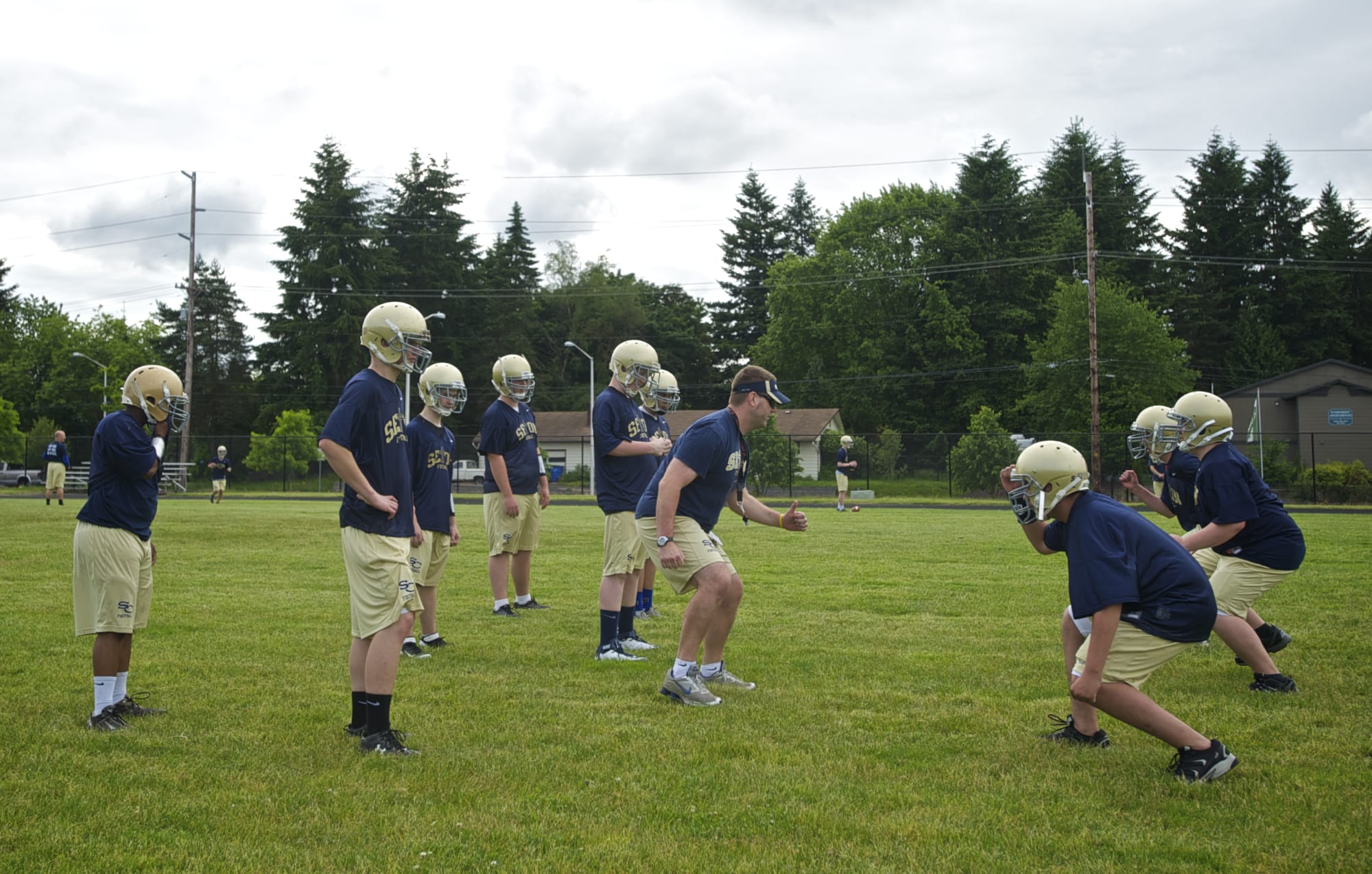 Seton Catholic High School offensive line coach Kasey Powers, center, puts players through a drill during football practice at Cascade Middel School on Thursday May 31, 2012.