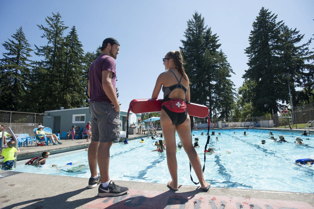 Seth Albert, 21, manager at Camas Municipal Pool, chats with lifeguard Laura Teames while keeping an eye on a busy pool.