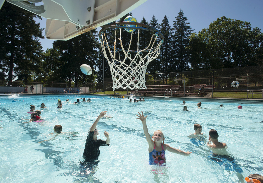 Alex Erickson, 8, of Camas, left, joins Caylee Wilcox, 9, of Vancouver as they take aim at the basketball hoop Aug. 12, 2016, at Camas Municipal Pool.