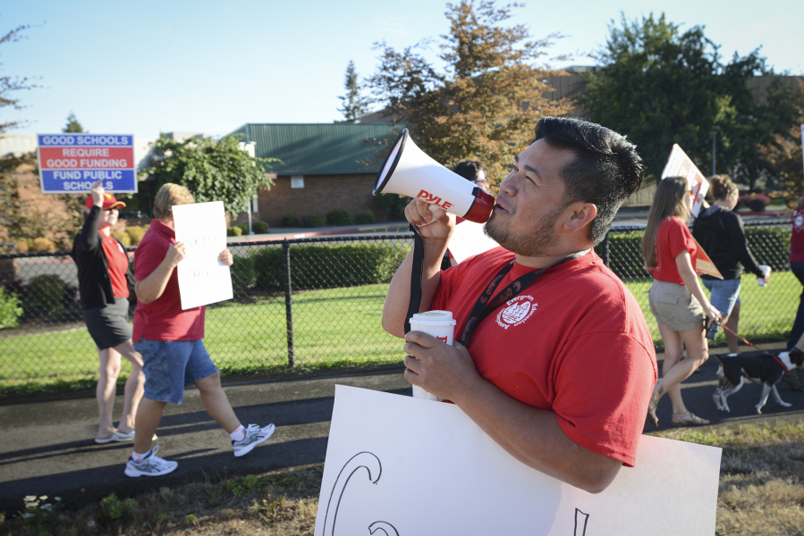 Kosal Sam, a Cascade Middle School sixth-grade math teacher, leads a chant Friday at Evergreen High School for picketers who want contract negotiations.