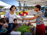 Jacky Yang of Yang&#039;s Fresh Bloomer and Produce hands a bouquet of flowers to Pamela Roberts at the farmers market in east Vancouver Aug. 4. The market is in its second year as the Columbia Tech Center looks to build a sense of community on the east side of the city.