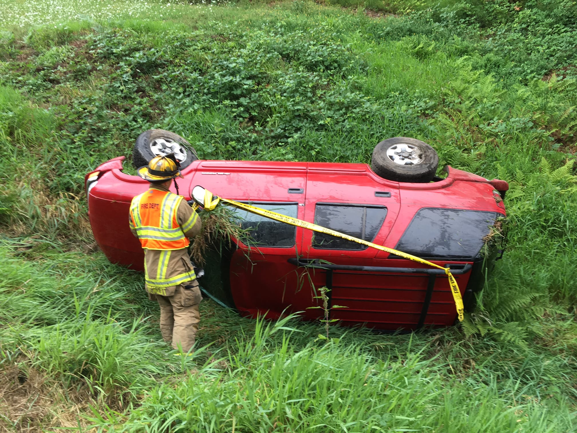 A firefighter responds following a rollover crash near Daybreak Park around 11:30 a.m. Wednesday. No one was seriously hurt, but officials are reminding drivers that the first rain after a long dry period is bringing up oil in the roadways, making them extra slick.