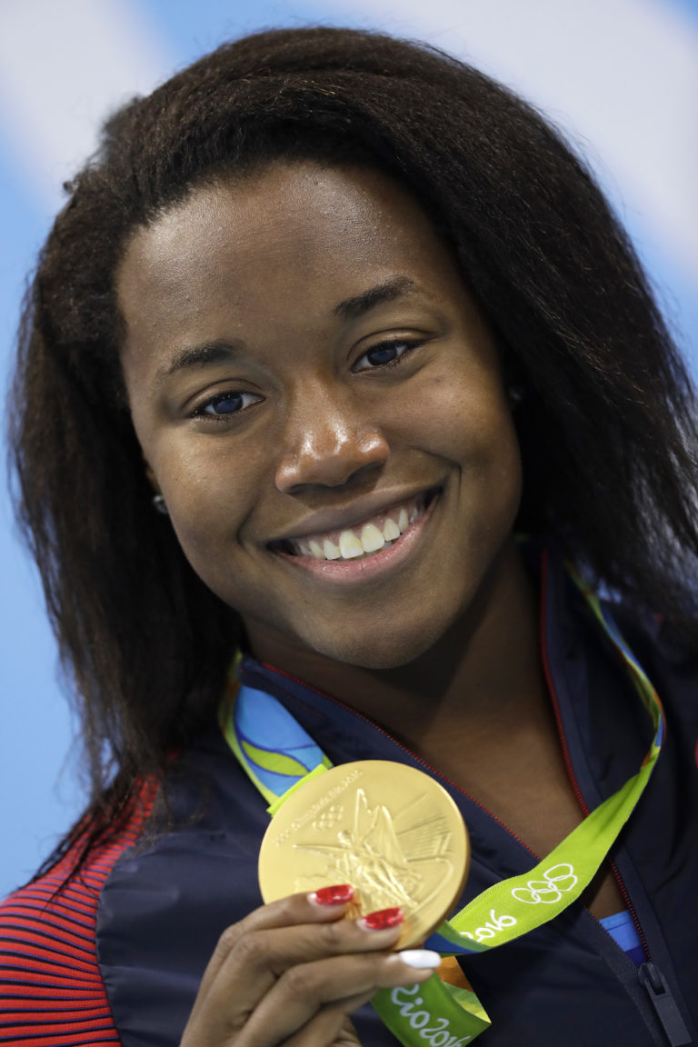 United States' Simone Manuel shows off her gold medal during the medal ceremony for the women's 100-meter freestyle final during the swimming competitions at the 2016 Summer Olympics, Friday, Aug. 12, 2016, in Rio de Janeiro, Brazil.