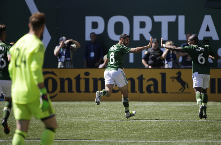 Seattle Sounders goalkeeper Stefan Frei, left, watches as Portland Timbers' Diego Valeri (8) and Darlington Nagbe (6) celebrate after Timbers' Fanendo Adi (not shown) scored a goal in the first half of an MLS soccer match, Sunday, Aug. 28, 2016, in Portland, Ore. (AP Photo/Ted S.