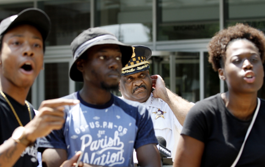 Chicago Police Superintendent Eddie Johnson, at rear, is blocked by three protesters as he tries to deliver a written statement about the release of police shooting video to reporters outside Friday outside police headquarters in Chicago.