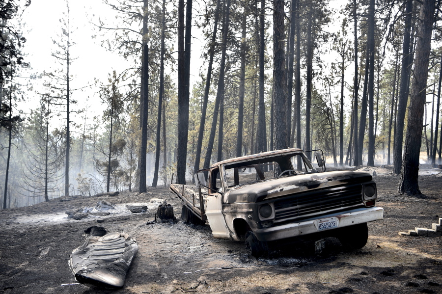A charred truck is seen near the home of Julie Thayer and her husband, Art, on South Yale Road near Valleyford, Wash., on Monday. The Thayers had been hiking over the weekend and returned home Sunday night to find their home destroyed.