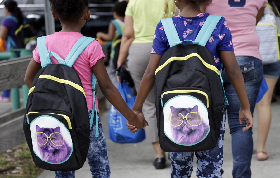 Children hold hands as they walk with their new book bags in Miami. The lazy days of summer are ending for millions of children as they grab their backpacks, pencils and notebooks and return to the classroom for a new school year.
