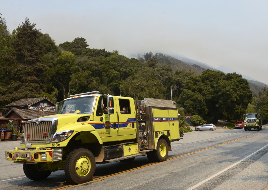 A fire engine passes the Ripplewood Resort as a smoke from a firing operation is visible in the Juan Higuera Creek drainage above as crews fight a wildfire near the village of Big Sur, Calif., on Saturday.