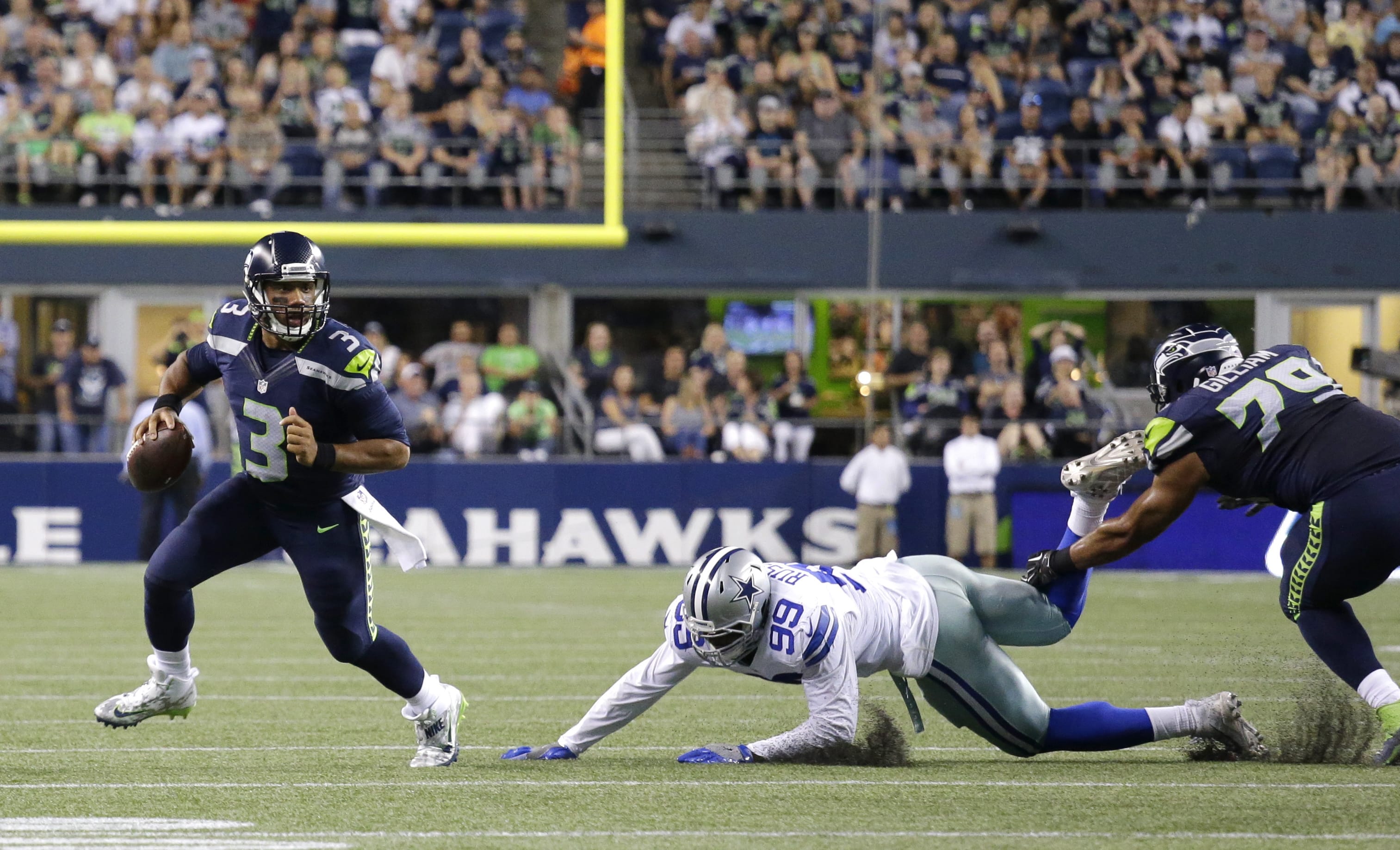 Seattle Seahawks quarterback Russell Wilson (3) scrambles away from Dallas Cowboys defensive end Ryan Russell (99) before throwing a touchdown pass to Tyler Lockett, not seen, duirng the second half of a preseason NFL football game, Thursday, Aug. 25, 2016, in Seattle.