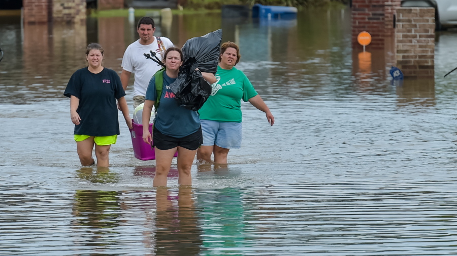 People wade in water near flood damaged homes in Highland Ridge Subdivision in Youngsville, La., on Sunday. Torrential rains swamped parts of southern Louisiana, causing widespread flooding.