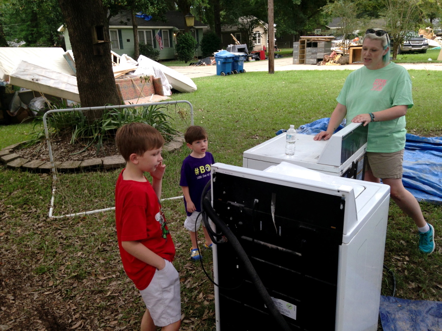 Amanda Burge looks at flood damaged items with two of her three children Aiden, left, and Hudson, center, in Denham Springs, La., Friday, Aug. 19, 2016. "Everything is gone. School is gone. Home is gone. Church is gone," said Burge, president of the Parent Teacher Organization at Denham Springs Elementary School.