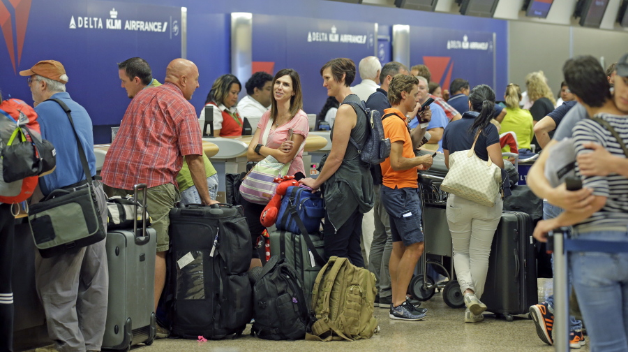 Passengers stand in line after Delta Air Lines flights resumed Monday in Salt Lake City, following a computer outage. Delta Air Lines delayed or canceled hundreds of flights Monday after its computer systems crashed, stranding thousands of people on a busy travel day.