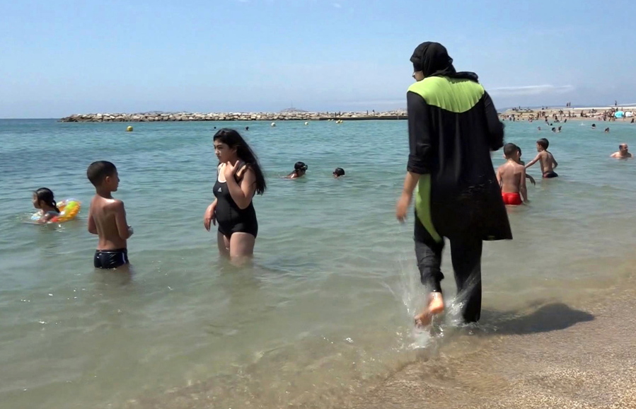 Nissrine Samali, 20, gets into the sea wearing a burkini, a wetsuit-like garment that also covers the head, in Marseille, southern France. Burkinis vs. bikinis.