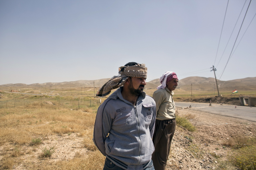Arkan Qassim, center, stands on May 19 at the site where he witnessed the killing dozens of Yazidi men including two sons of Rasho Qassim, right, in August 2014 in Hardan, northern Iraq. Both survivors said they simply want the graves exhumed.