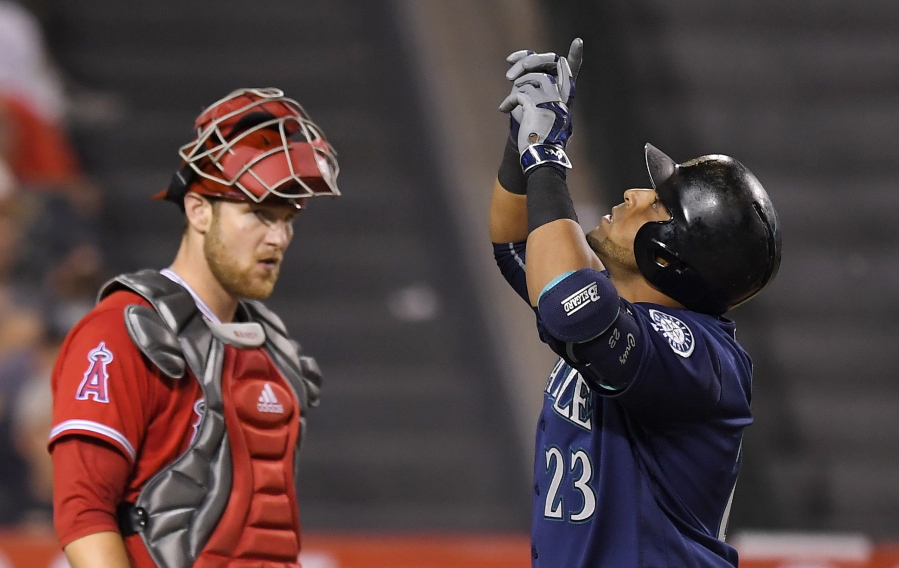 Seattle Mariners designated hitter Nelson Cruz, right, points to the sky after hitting a solo home run as Los Angeles Angels catcher Jett Bandy watches. (Mark J.