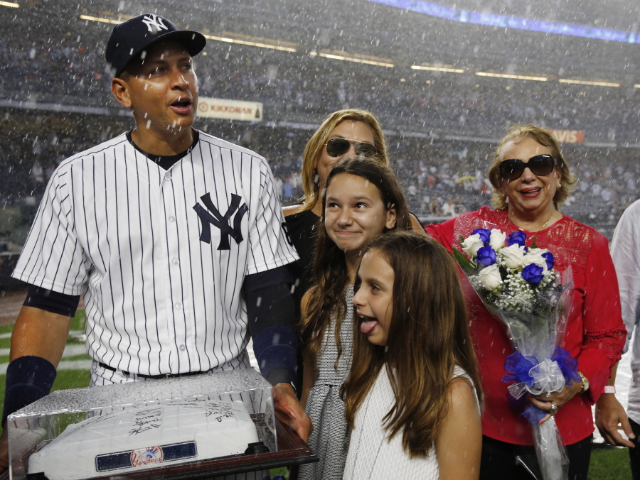 Alex Rodriguez reacts to a thunderstorm, while joined by his two daughters, mother, and another family members during a pre-game ceremony at Yankee Stadium.