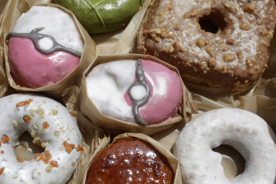 In this Friday, July 22, 2016, photo, Pecha Berry Pokeseed doughnuts, top left and center, are displayed in a box of doughnuts from Doughnut Plant, in New York.