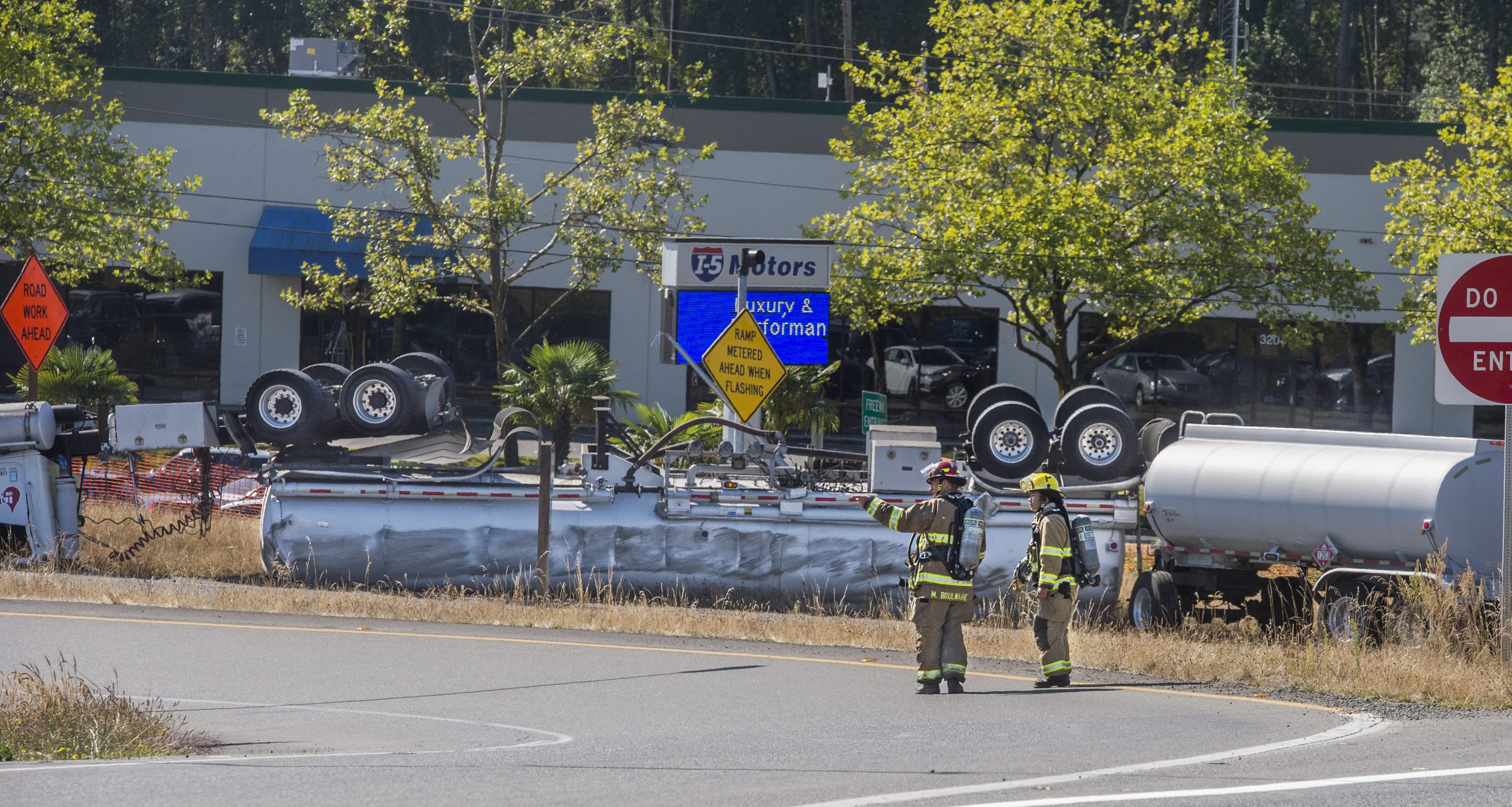 Firefighters stand near an overturned tanker truck at the Port of Tacoma Road entrance to Interstate 5, Thursday, Aug. 18, 2016 in Tacoma, Wash. A section of a major freeway in Washington state has reopened state after a tanker truck rolled over and spilled fuel near the Port of Tacoma.