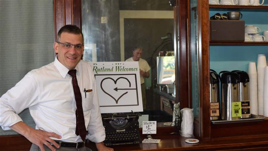 Mayor Christopher Louras with a sign promoting the volunteer group that is preparing to welcome Syrian refugees to Rutland, Vt. Some small cities and towns across the country see the new arrivals as a way to boost shrinking populations and improve sagging economies.