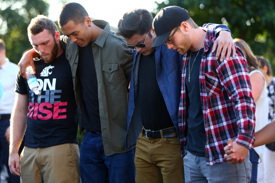Friends of the victims huddle together during a prayer July 31 as hundreds gather for a community vigil for the victims of a shooting that occurred early Saturday morning at a house in Mukilteo, killing three teenagers and wounding one.