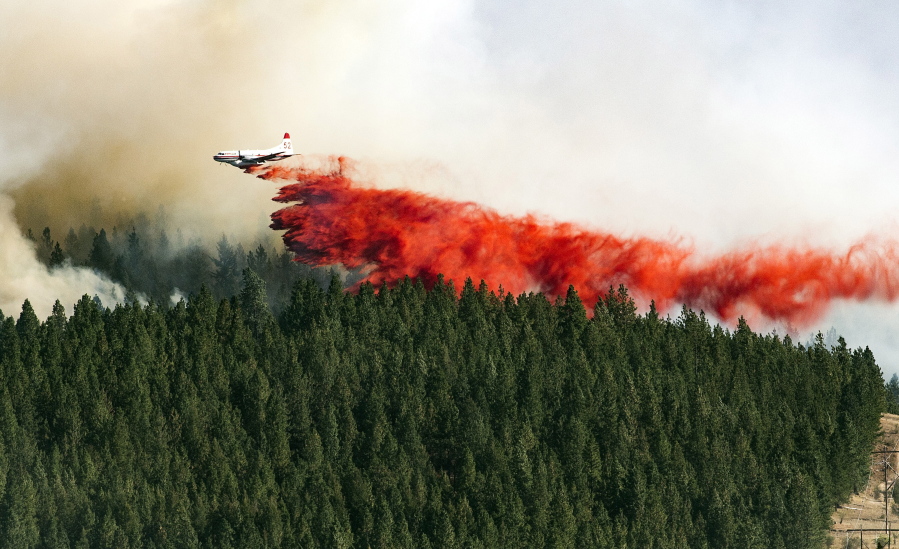 A  plane drops a load of fire retardant on the north side of Beacon Hill on Sunday in Spokane. The fast moving wildfire is threatening structures as it moves in a north-easterly direction.