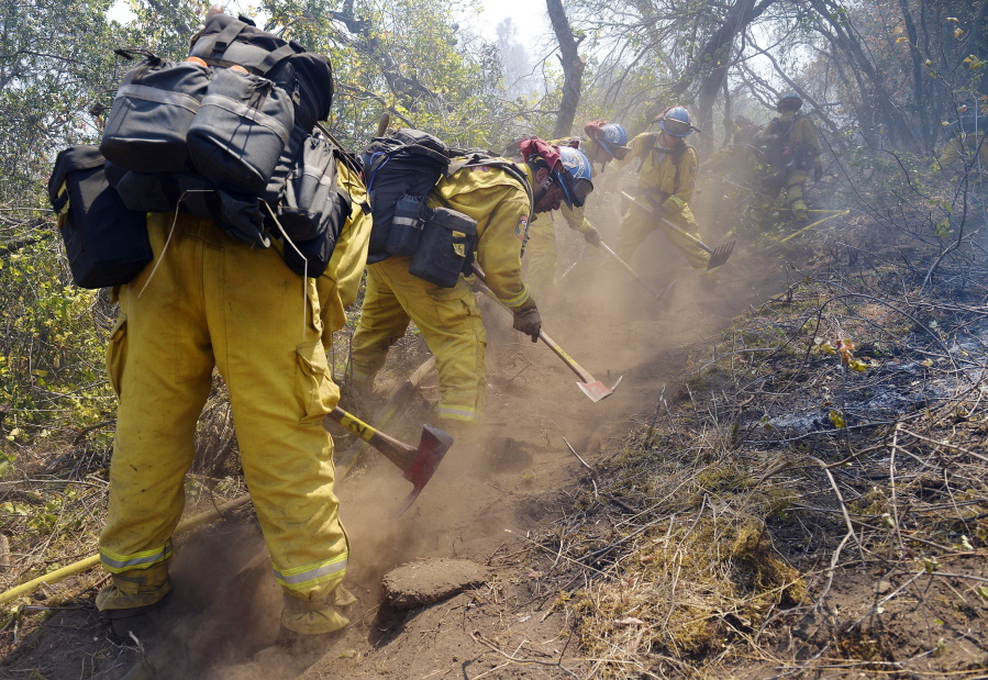 A work crew from the California Conservation Corps Butte County Fire Center cuts a line on Black Mountain near the town of Tollhouse, Calif., while fighting a blaze Monday.