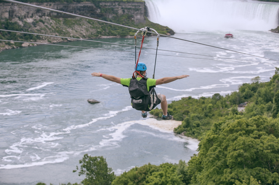 A tourist suspended above the water from zip lines makes his way at speeds of up to 40 mph toward the mist of the Horseshoe Falls, on the Ontario side of Niagara Falls. The overhead cables have evolved from a fun way to explore jungle canopies to trendy additions for long-established outdoor destinations.