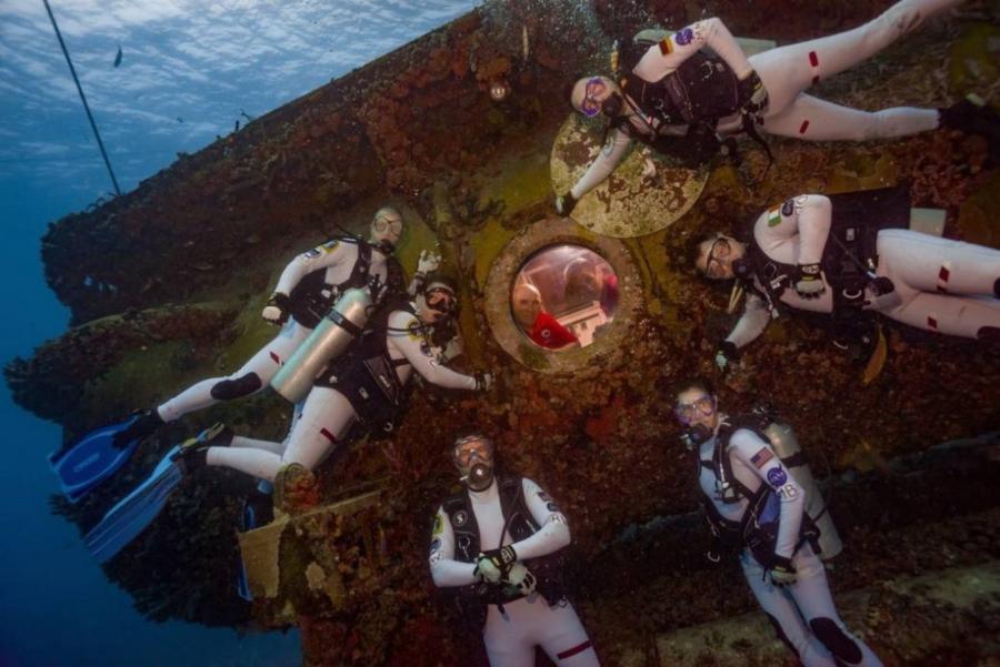 The mission team poses with habitat techs seated inside the Aquarius undersea habitat.